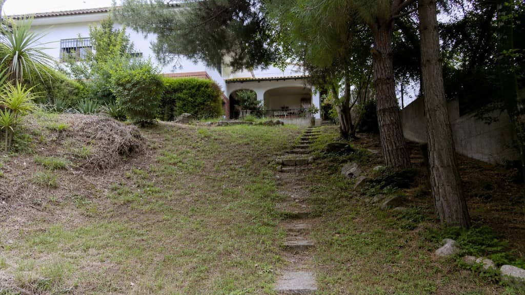 Jardín en pendiente de chalet antes de la reforma, con escalones de piedra