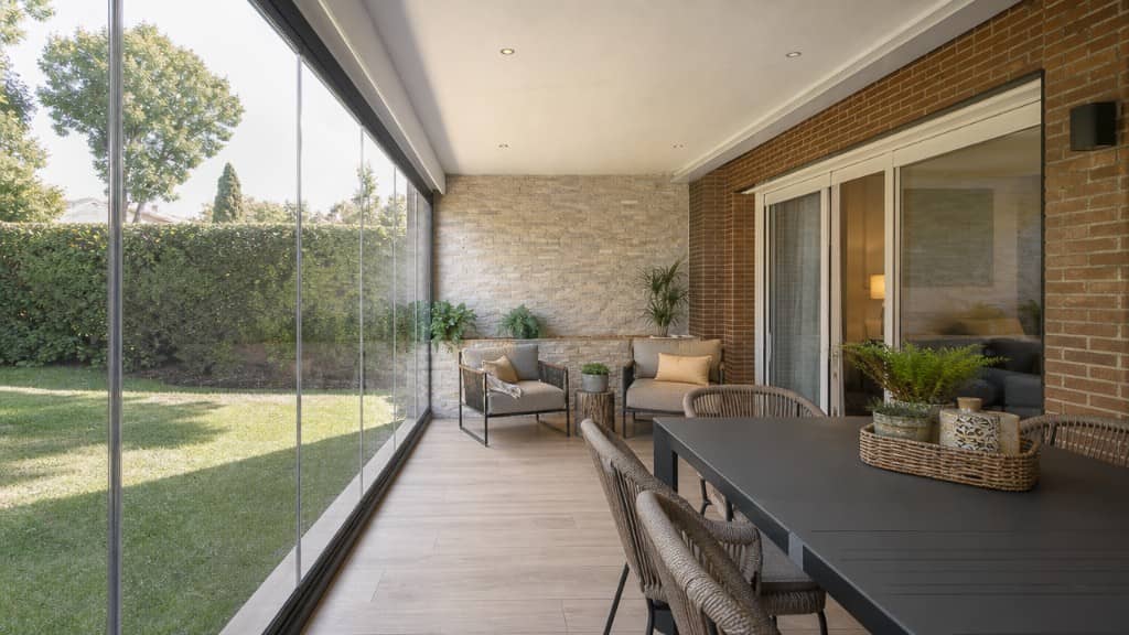 Porche cerrado con cortinas de cristal y zona de comedor en chalet