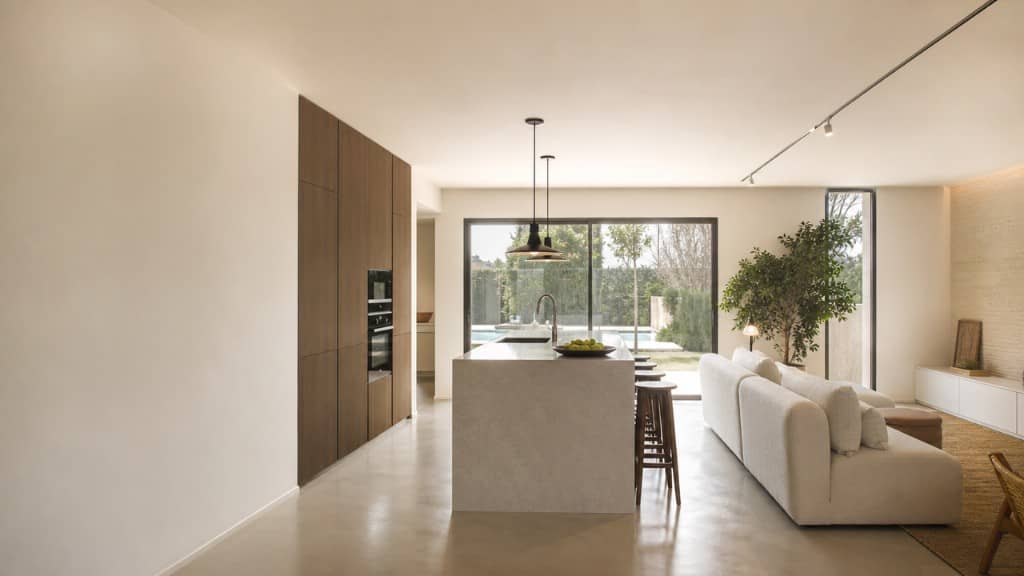 Cocina con isla abierta a zona de día y vistas a jardín con piscina en chalet
