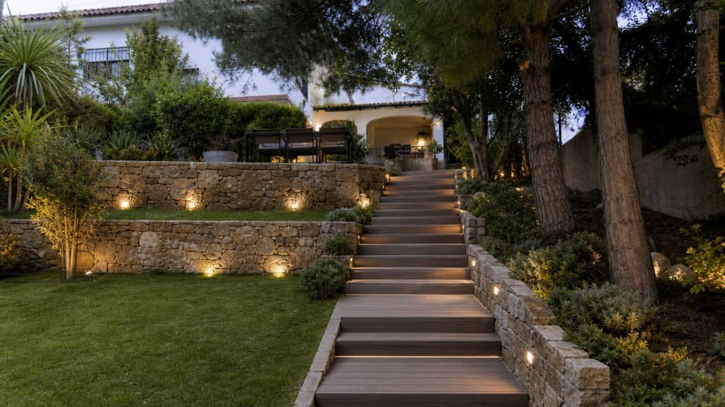 Jardín de chalet reformado con escalera LED, muros de piedra e iluminación