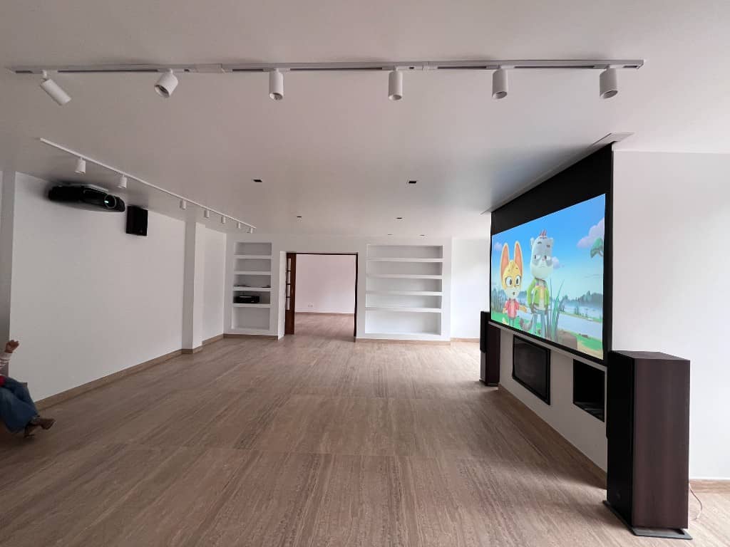 Salón reformado en chalet con pantalla retráctil, altavoces e iluminación en rail